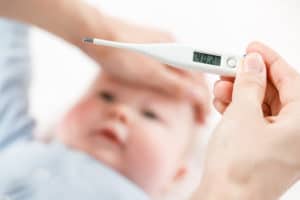 Mère mesurant la température de son enfant malade avec un thermomètre