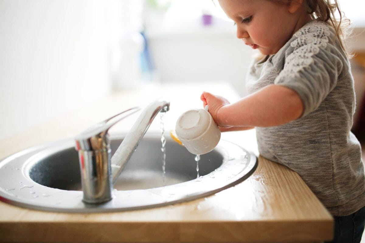 Enfant autonome nettoyant sa tasse tout seul selon la pédagogie Montessori
