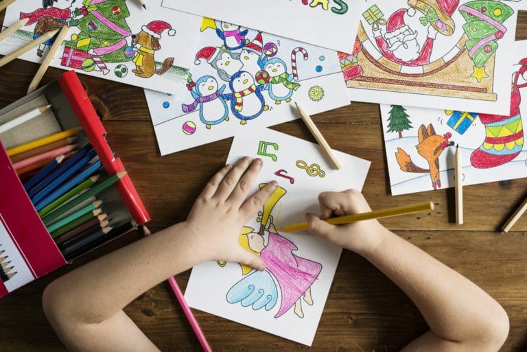Petite fille en train de dessiner et colorier avec des crayons de couleur
